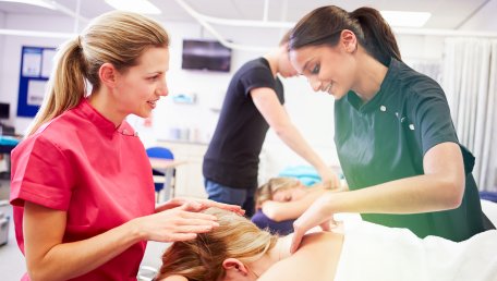 instructor works with a student practicing massage