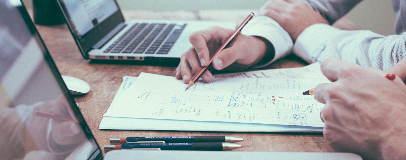 People doing paperwork next to a laptop
