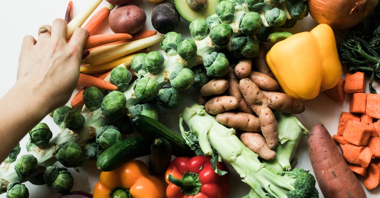A hand around an assortment of vegetables