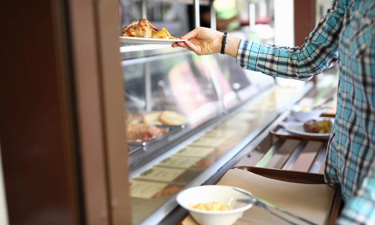 a student getting a plate of hot food from a dining hall