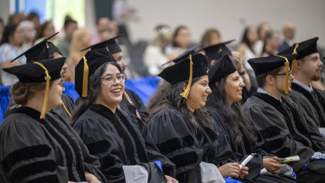 graduates, seated, smiling at Commencement Ceremony