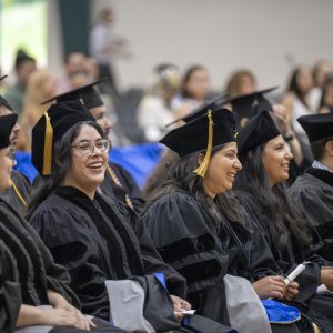 graduates, seated, smiling at Commencement Ceremony