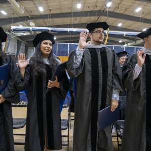 graduates with right hands raised reciting the oath