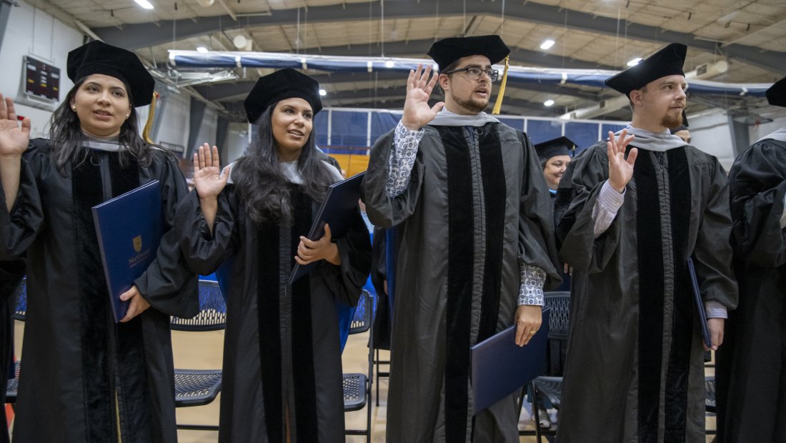 graduates with right hands raised reciting the oath