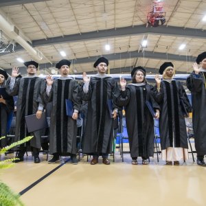 graduates with right hands raised reciting the oath