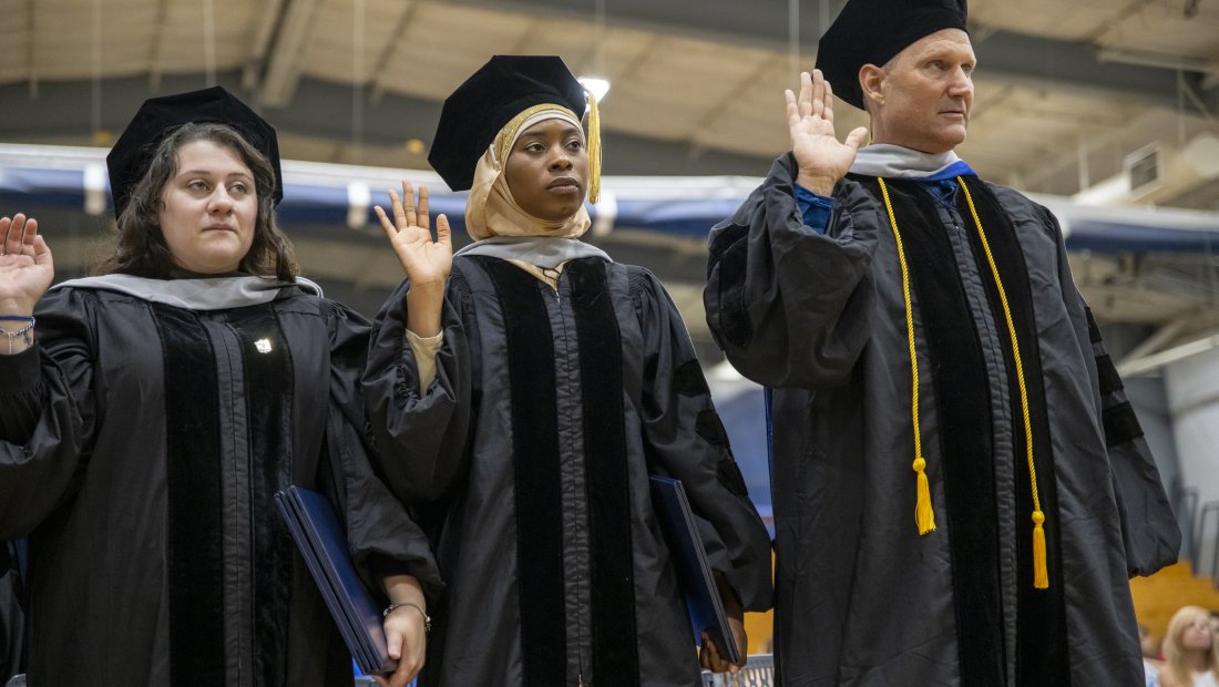 graduates with right hands raised reciting the oath