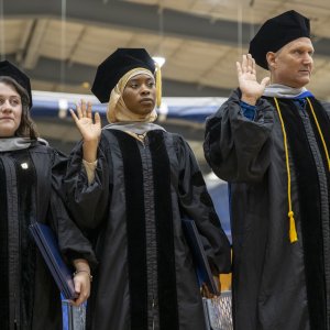 graduates with right hands raised reciting the oath