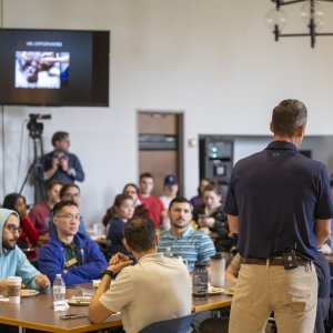 photo from behind Dr. Kollmann as he speaks to the crowd