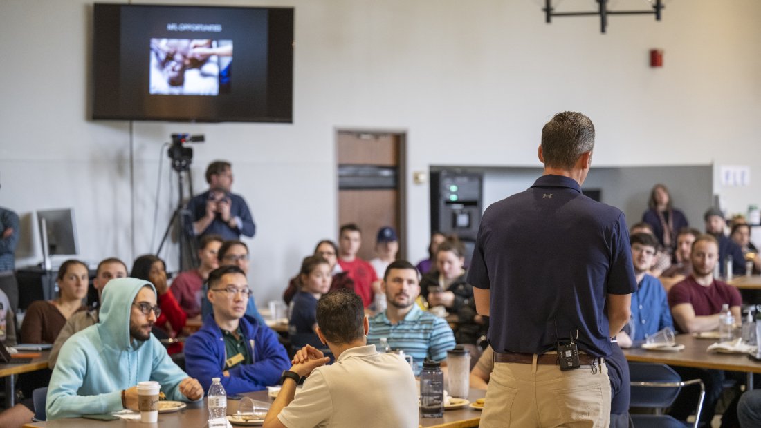 photo from behind Dr. Kollmann as he speaks to the crowd