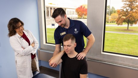 an instructor observes a student working with a patient