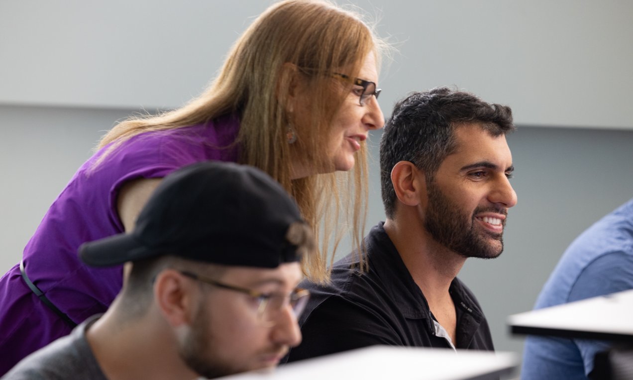 an instructor assists a student in a computer lab
