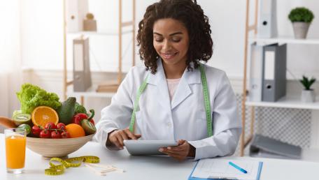 Nutritionist reviewing notes, sitting with a bowl of fruit
