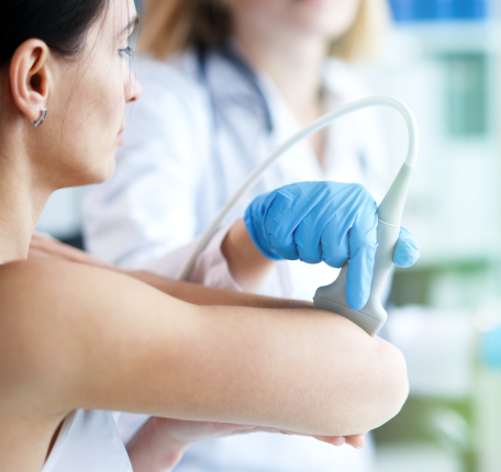 Diagnostic medical sonography student performs an ultrasound scan using a handheld transducer in a clinical lab setting.